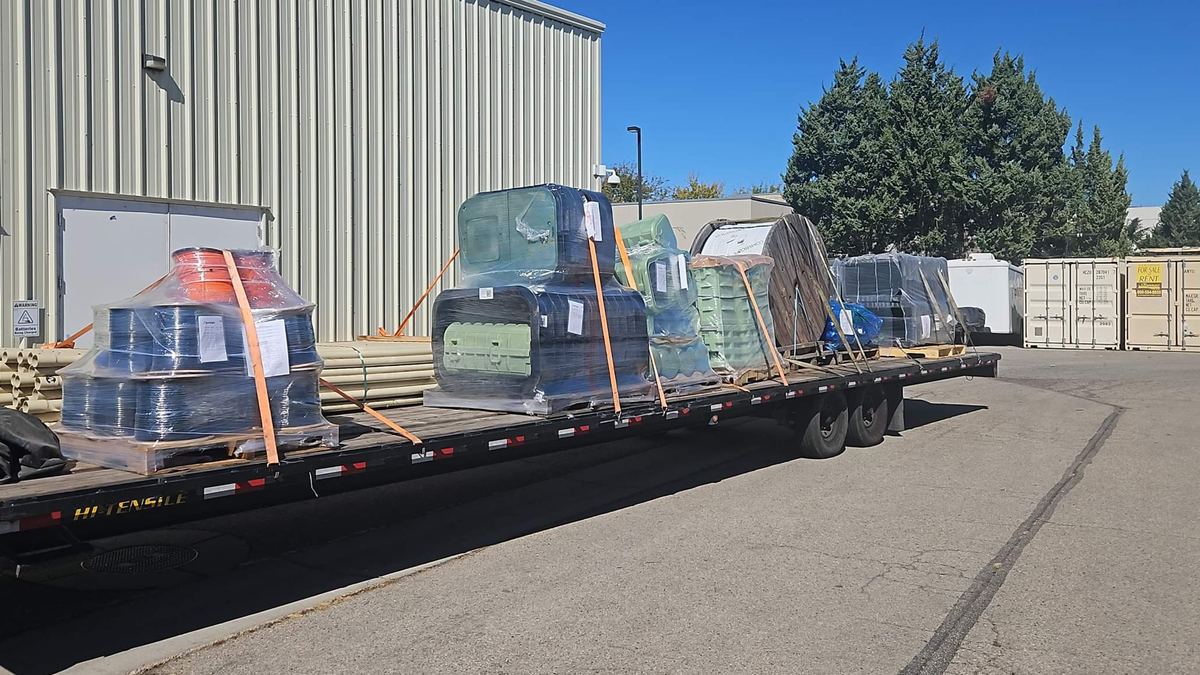 Palletized freight strapped on an EXMULI gooseneck flatbed trailer